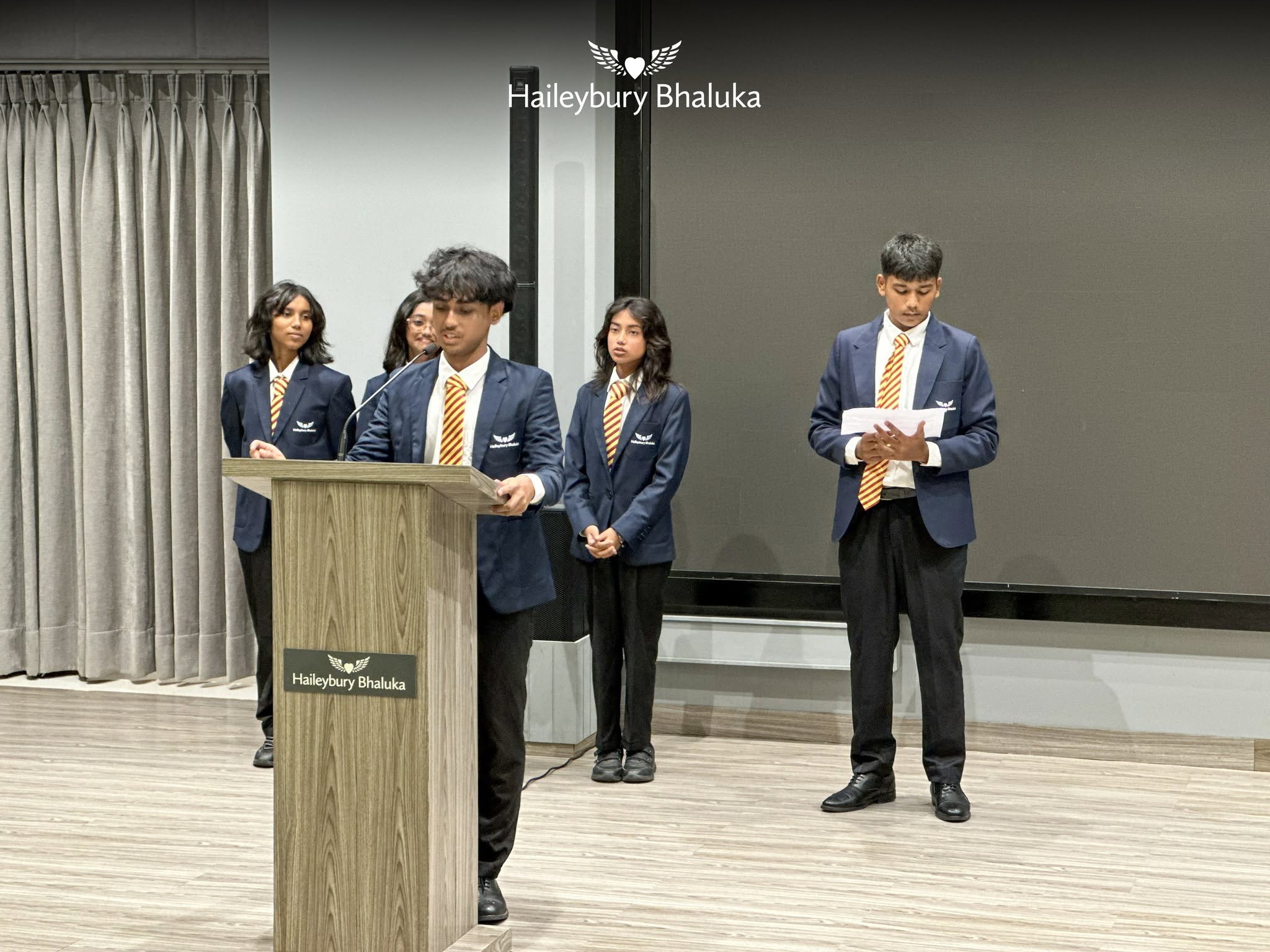Students presenting about butterflies and transformation at Haileybury Bhaluka assembly